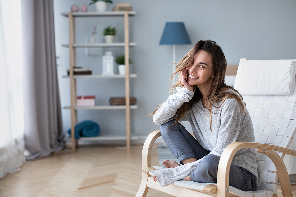 beautiful happy woman looking at camera and smiling while sitting in a cozy chair
