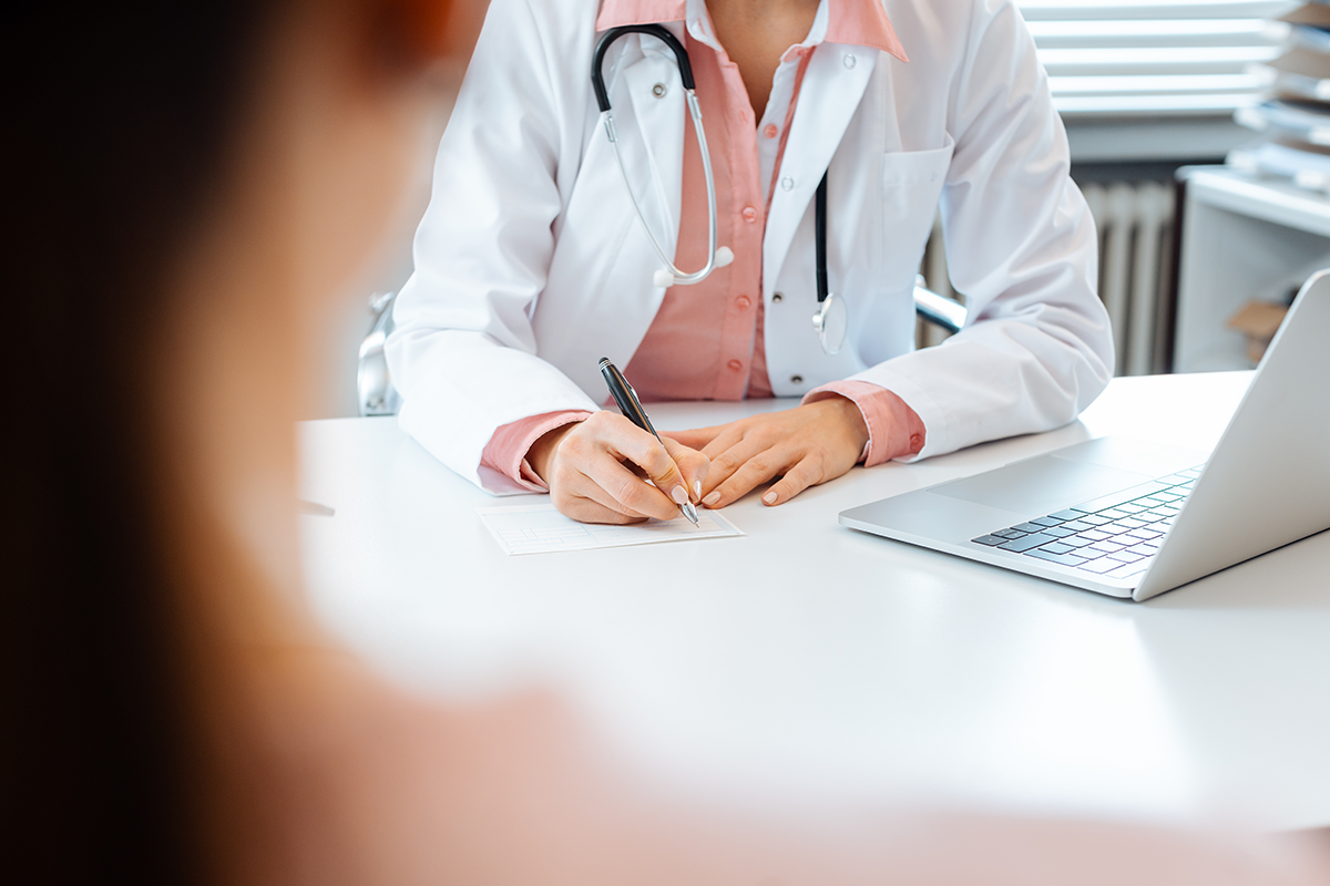 close up of doctor taking notes while having appointment with patient