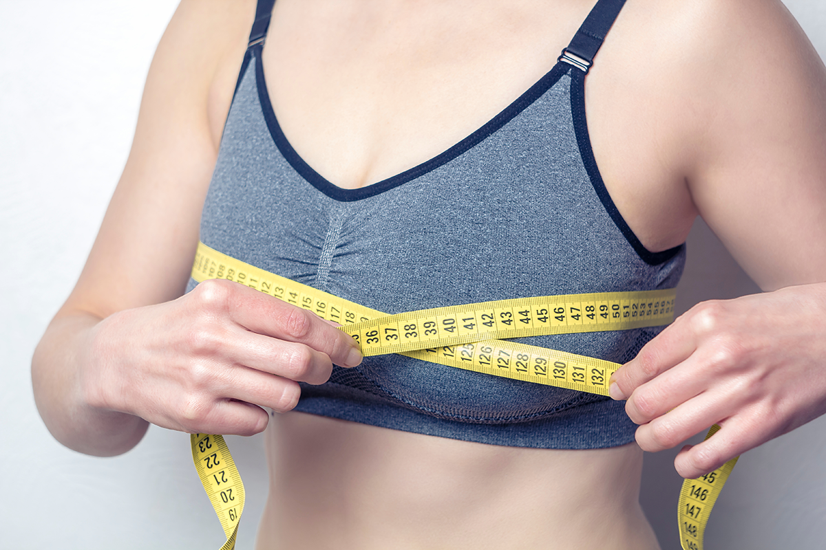 closeup of young woman measures her breast with a measuring tape