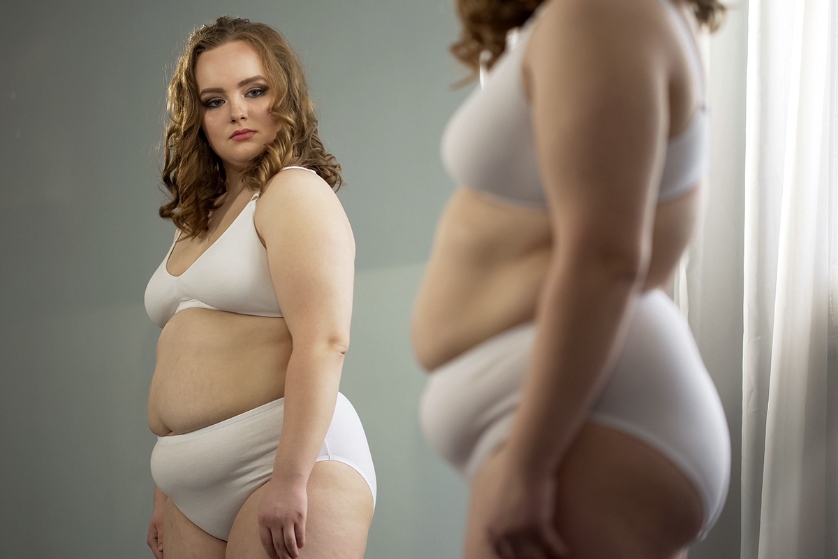 fat lady attentively looking at her mirror reflection