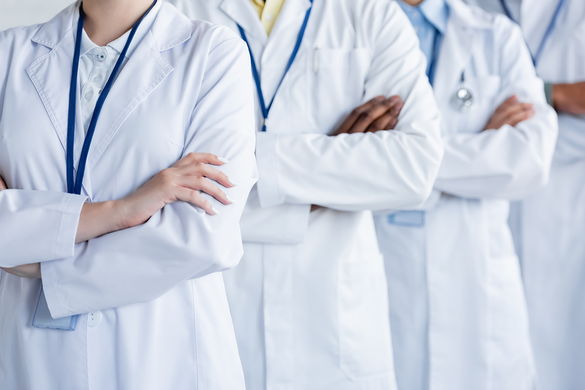 multicultural doctors in white coats standing with crossed arms